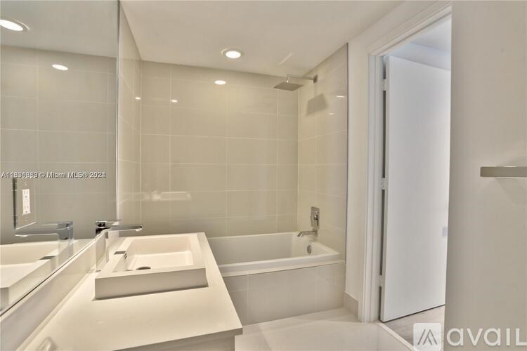 A modern bathroom with a white sink and bathtub.