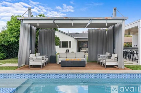 A poolside patio area with a white sofa and grey curtains.