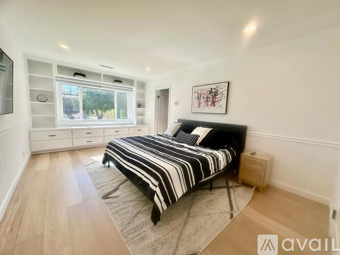 A bedroom with a large bed and a window with a view of trees.