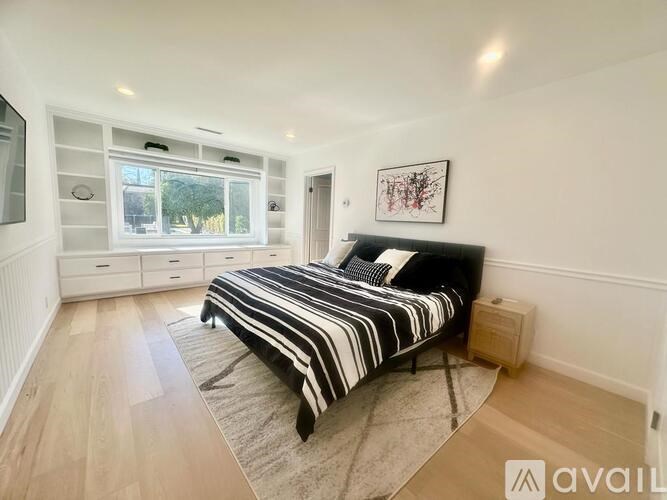 A bedroom with a large bed and a window with a view of trees.