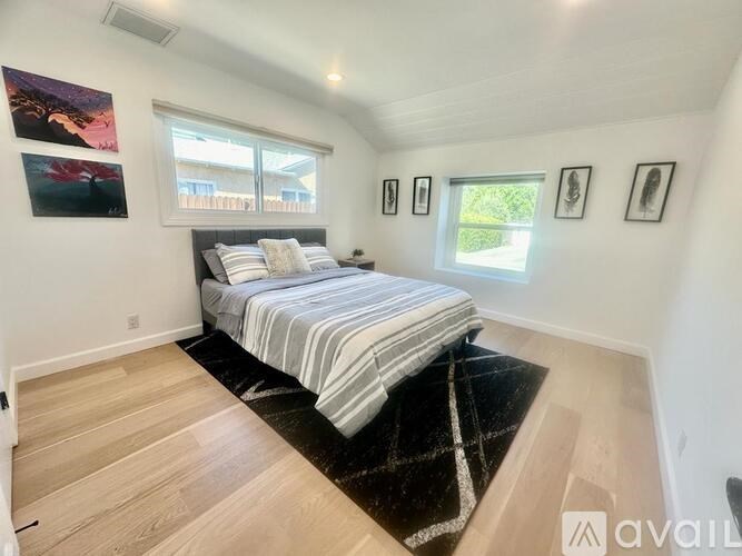 A bedroom with a bed, a rug, and pictures on the wall.