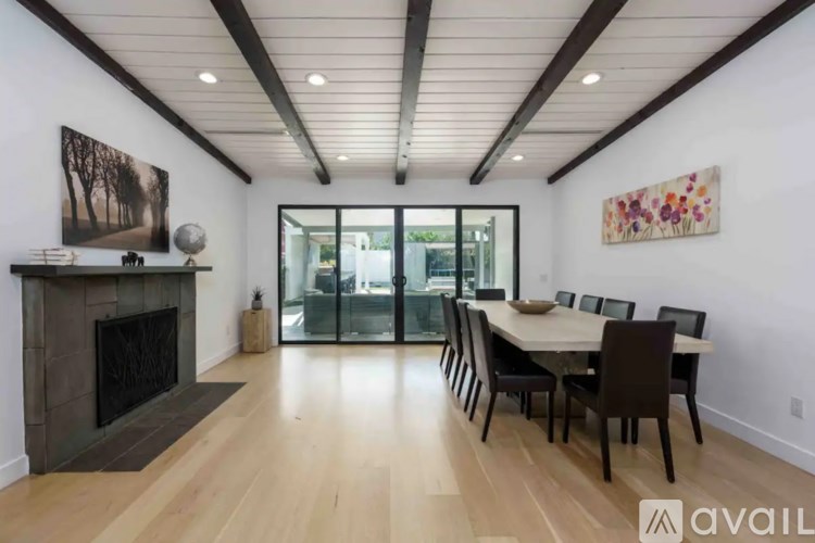 A modern dining room with a fireplace and a large painting on the wall.