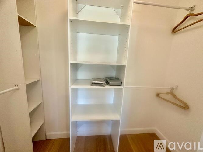 A white closet with a hanger and a shelf with a box on it.