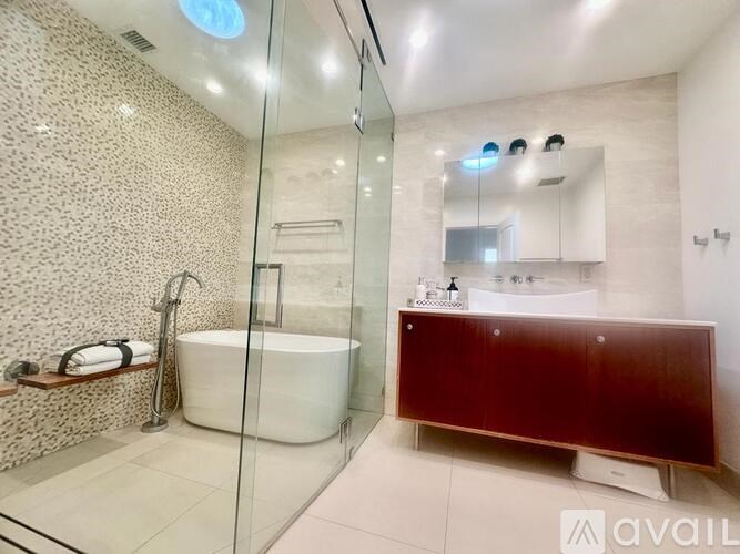 A modern bathroom with a glass shower and a white bathtub.