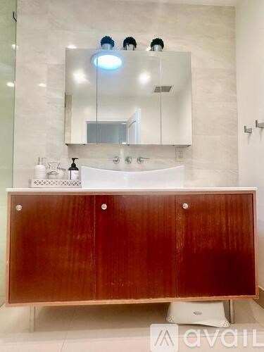 A bathroom with a sink, mirror, and wooden cabinet.