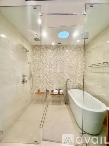 A bathroom with a glass shower enclosure and a white bathtub.