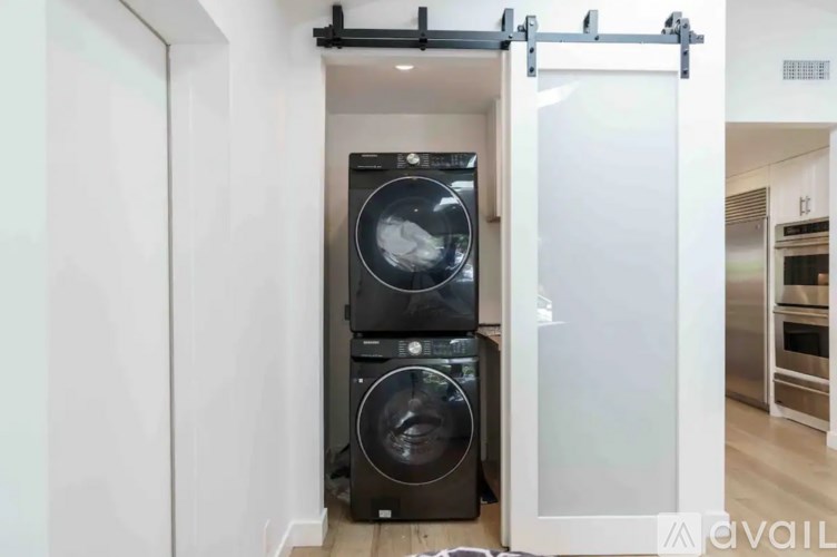 A stack of three black washing machines in a small laundry room.