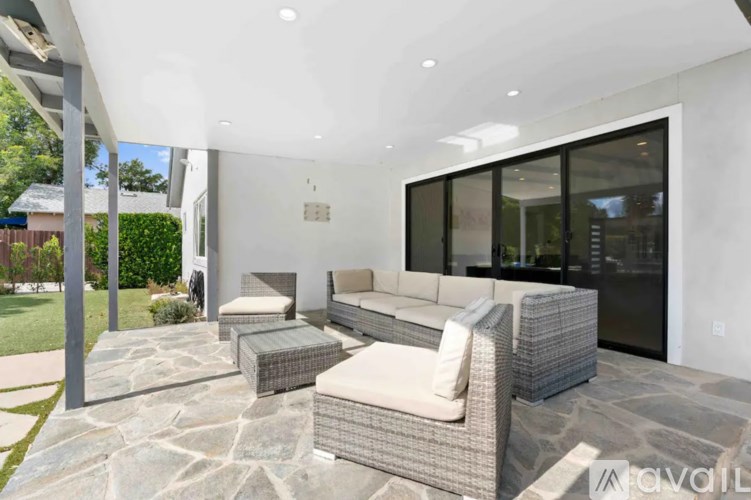 A modern outdoor seating area with a stone floor and a glass door.