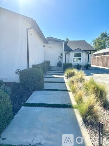 A white house with a concrete pathway leading to the front door.