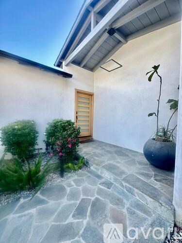 A small garden with a stone pathway leading to a wooden door.