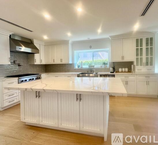 A modern kitchen with white cabinets and a marble countertop.