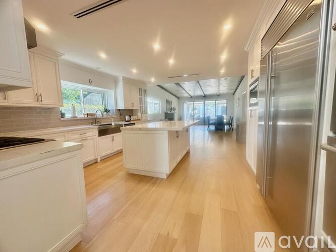 A spacious kitchen with white cabinets and a wooden floor.