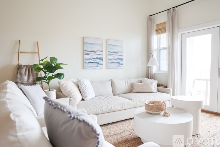 A white couch with a plant on it and two pictures on the wall.