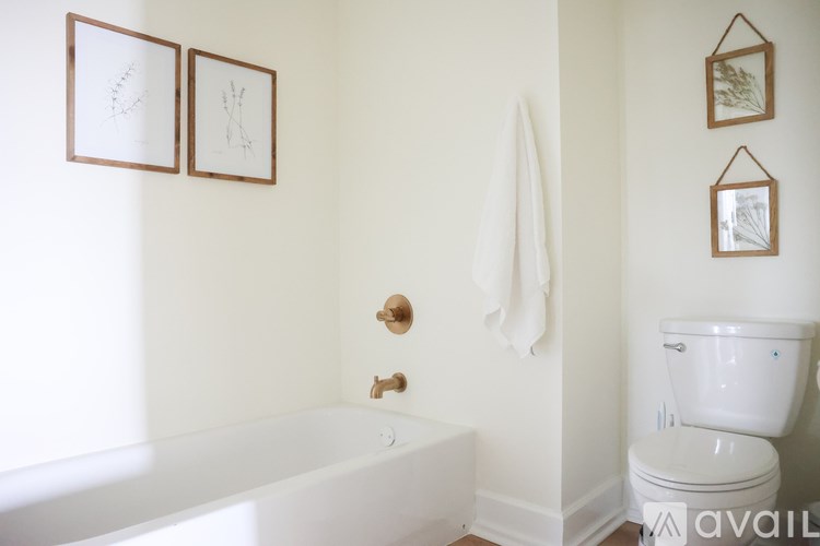 A white bathroom with a toilet, tub, and pictures on the wall.