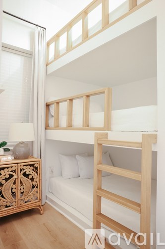 A wooden bunk bed in a room with a white sofa and a wooden cabinet.