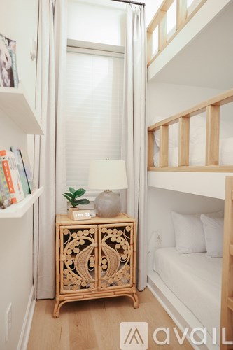 A small room with a bunk bed, a nightstand with a plant, and a wooden cabinet.