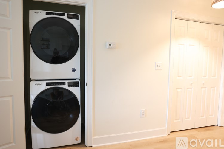 A white front loading washing machine in a room with a white door.