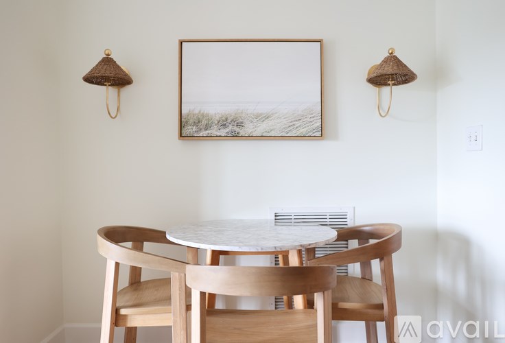 A white table with four chairs and a picture frame on the wall.