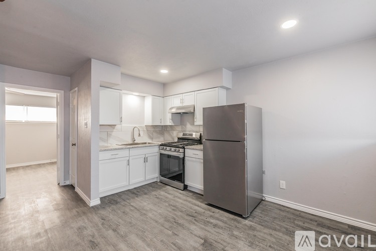 A kitchen with a refrigerator, oven, and sink.