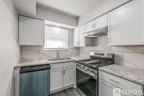 A modern kitchen with white cabinets and stainless steel appliances.