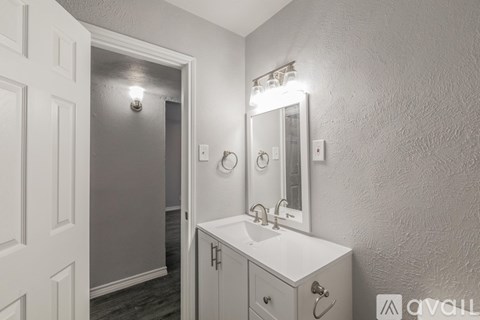 A bathroom with a sink, mirror, and a door.