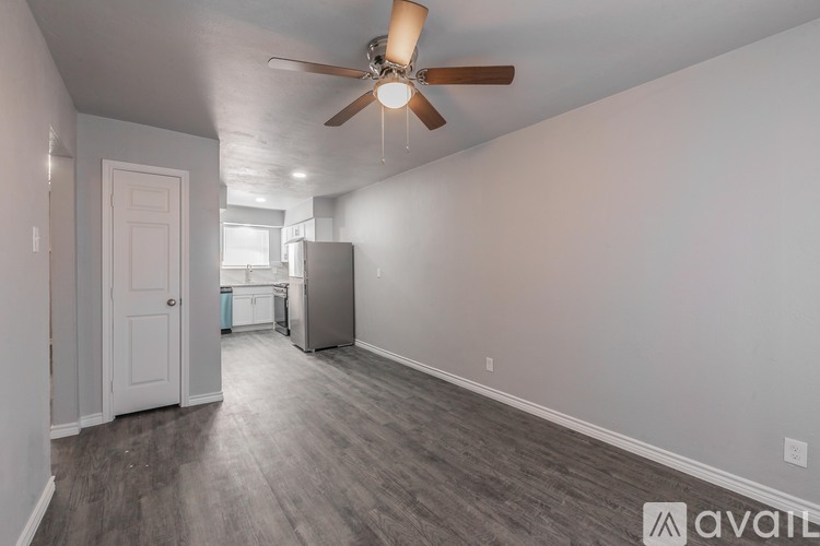 A room with a ceiling fan and a refrigerator.