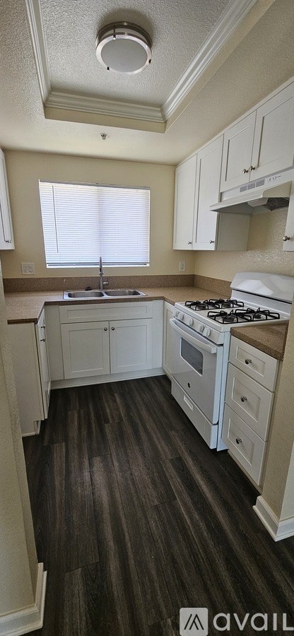 A kitchen with white cabinets and a white stove top oven.