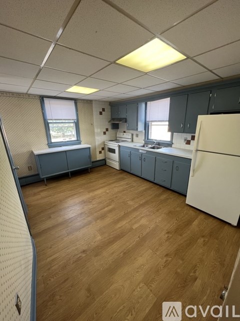 A kitchen with wooden floors and a white refrigerator.
