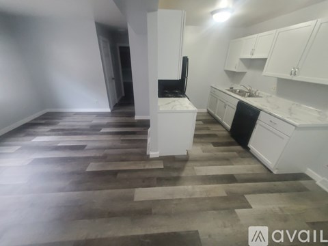 A kitchen with white cabinets and a wooden floor.