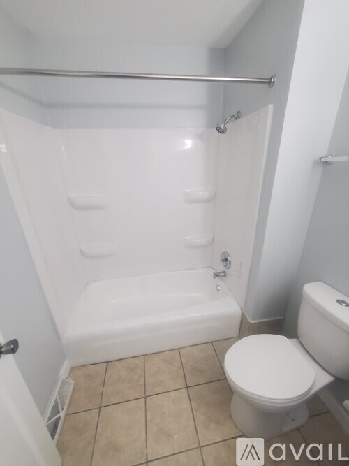 A white toilet sits next to a bathtub in a bathroom.