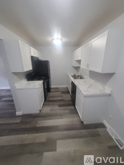A kitchen with white cabinets and a black fridge.