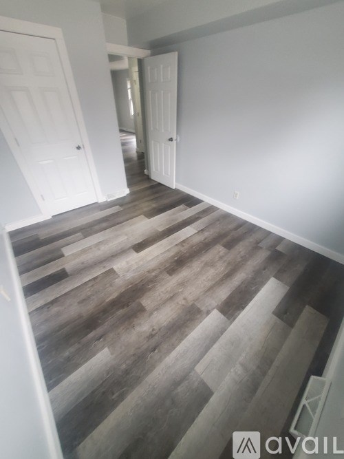 A hallway with a wooden floor and white walls.