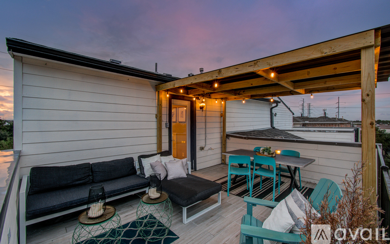 A wooden deck with a black couch and a table with chairs.