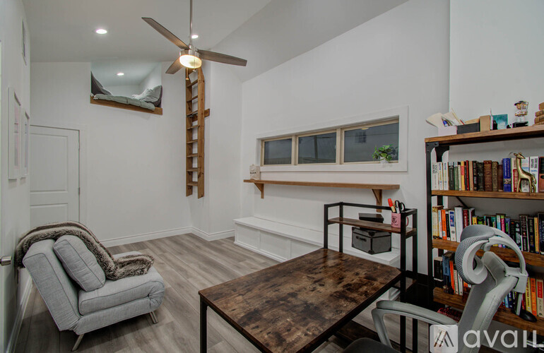 A living room with a grey armchair, a wooden coffee table, and a bookshelf filled with books.