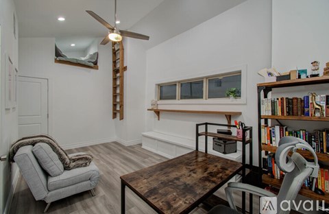 A living room with a grey armchair, a wooden coffee table, and a bookshelf filled with books.