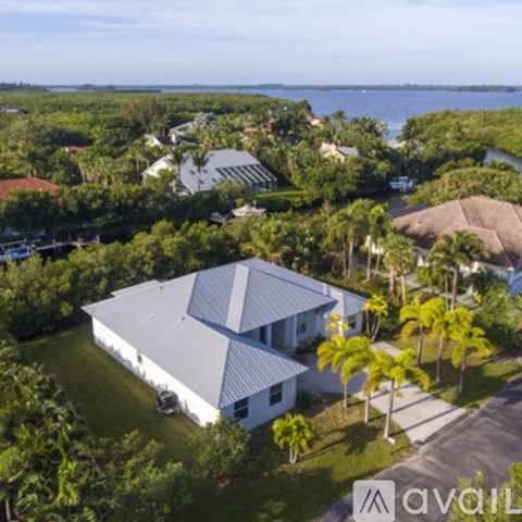 A house with a white roof and a grey roof is surrounded by trees.