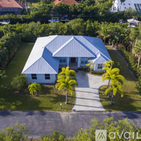 A house with a blue roof and white walls surrounded by greenery.