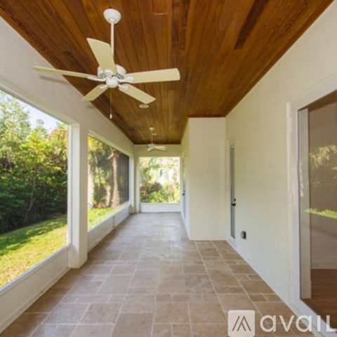 A long hallway with a ceiling fan and tiled floor.