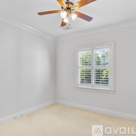A room with a ceiling fan and a window with blinds.