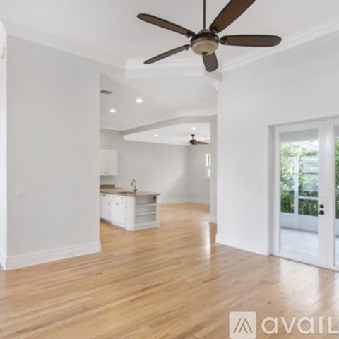 A spacious room with a ceiling fan and wooden flooring.