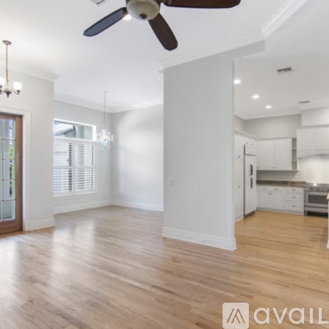 A spacious kitchen and living room with hardwood floors and white walls.