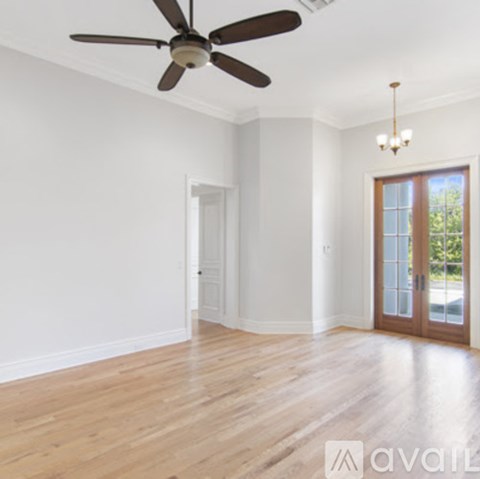 A room with a ceiling fan and wooden flooring.