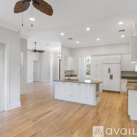 A spacious kitchen with white cabinets and a wooden floor.