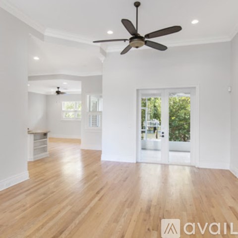 A spacious room with wooden floors and a ceiling fan.