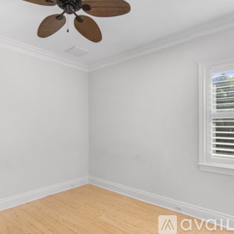 A room with a ceiling fan and a window with blinds.