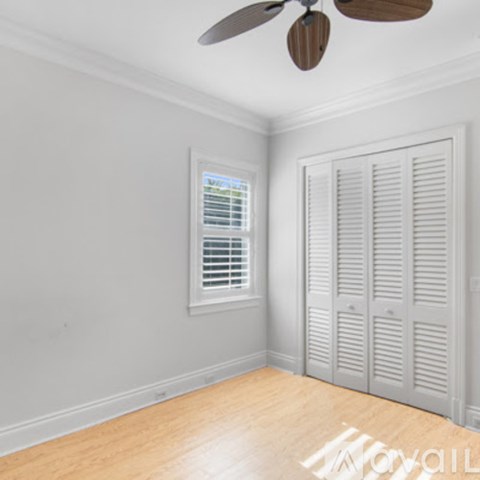 A room with a ceiling fan and a window with blinds.