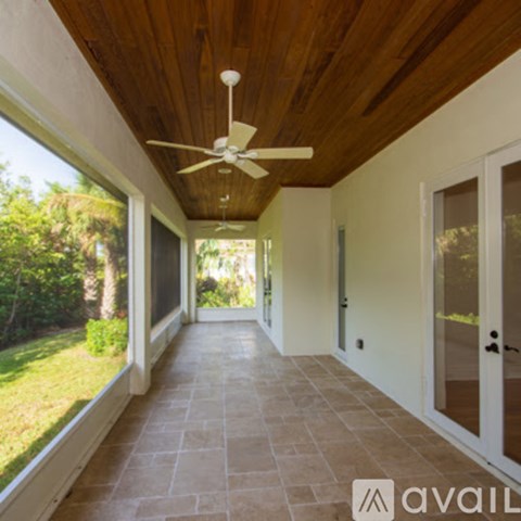 A long hallway with a ceiling fan and sliding glass doors.