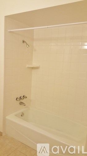 A white bathtub with a shower head and faucet.