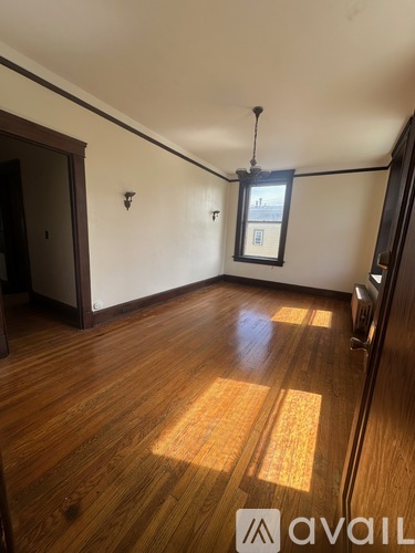 A room with wooden floors and a window with a view of a building outside.