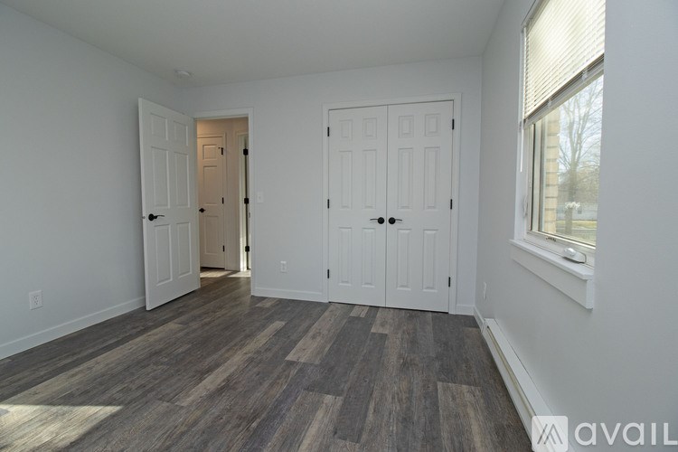 A room with a wooden floor and two white doors.